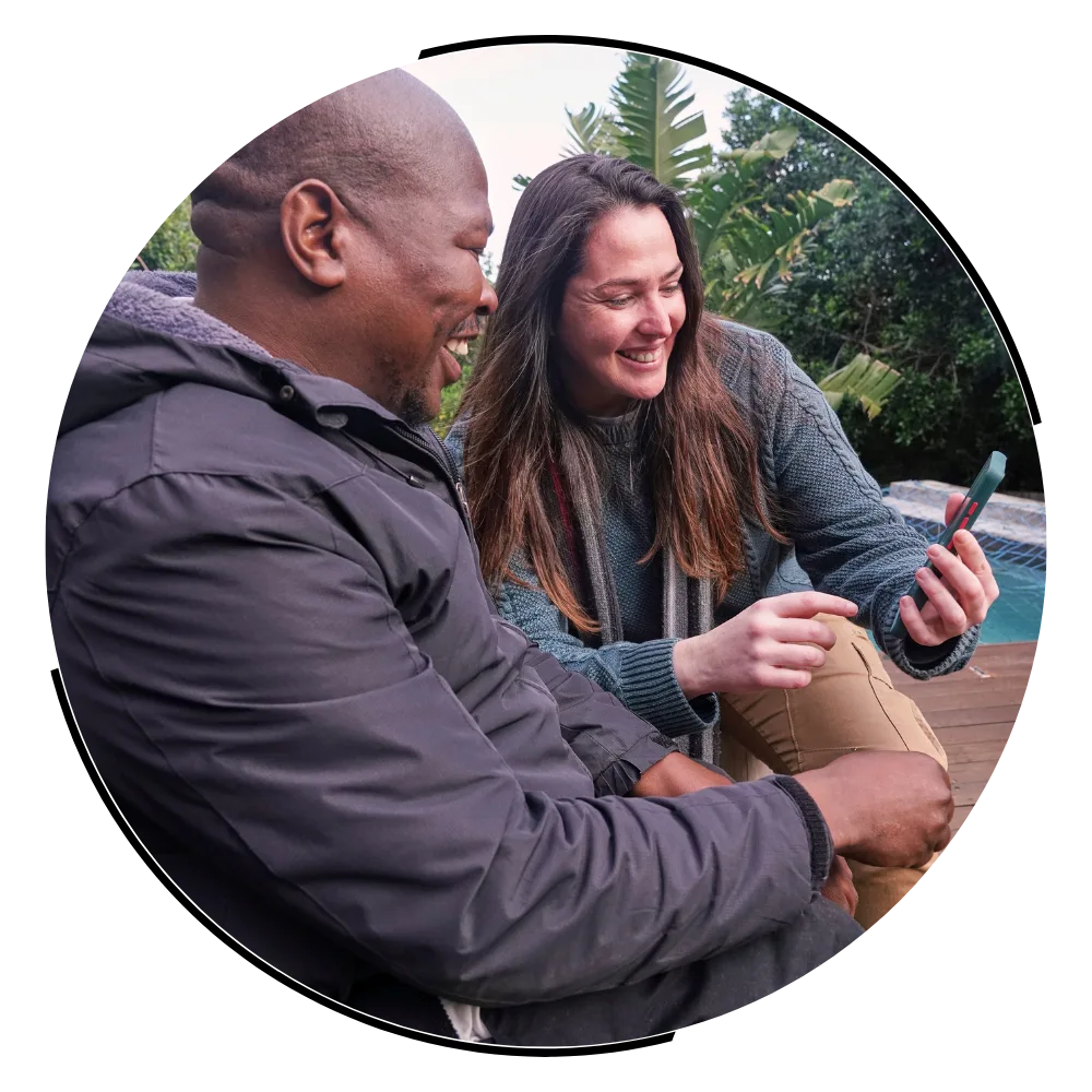 Disabled man in wheelchair smiling with support worker using mobile phone to contact Gentle Touch