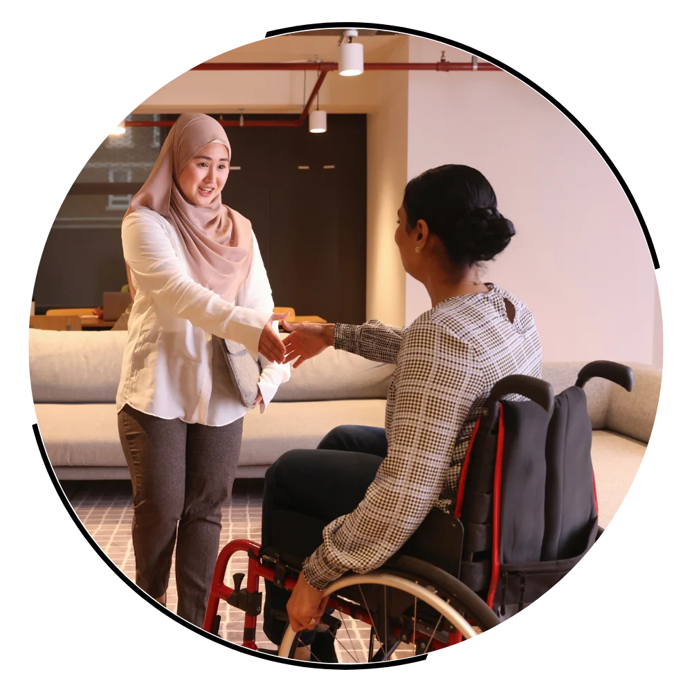 Disabled woman in wheelchair shaking hands with support worker